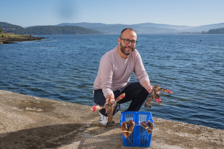 Fernando Ríos sujetando dos bogavantes al borde de la ría.