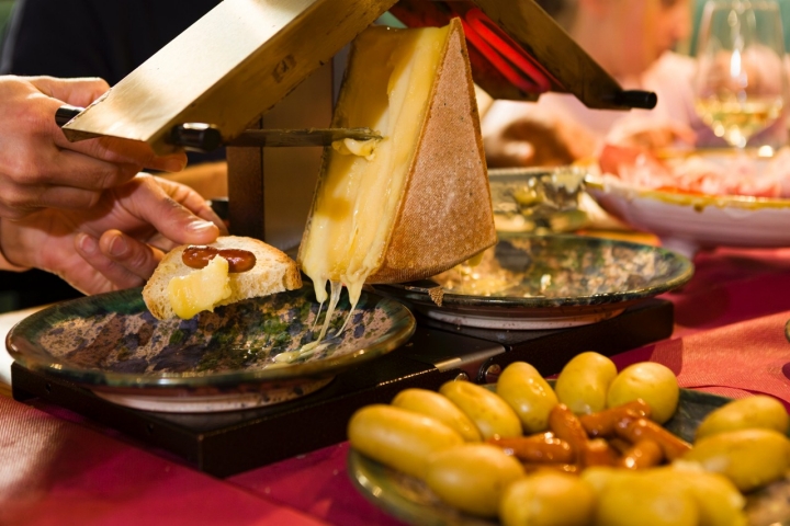 Untando el queso en un trozo de pan tras fundirse en la raclette. 