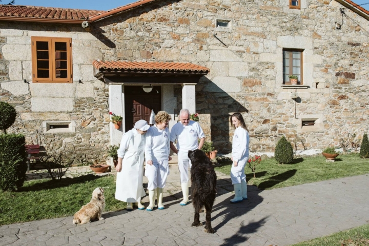 Tres generaciones queseras, perros incluidos, ante la casa familiar.