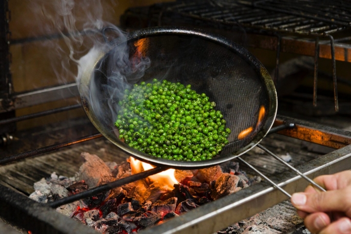 Los guisantes cogen el punto ahumado acariciados por el fuego