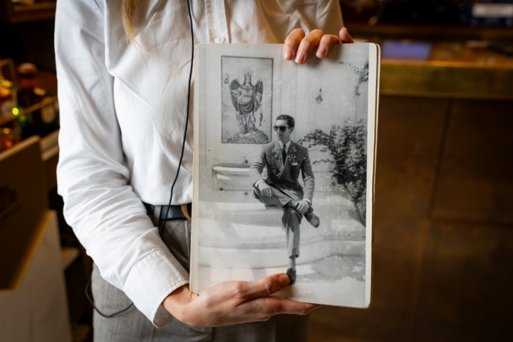 Una fotografía de Manolete sentado en la fuente de azulejos en blanco y azul que muestran la figura de San Rafael.
