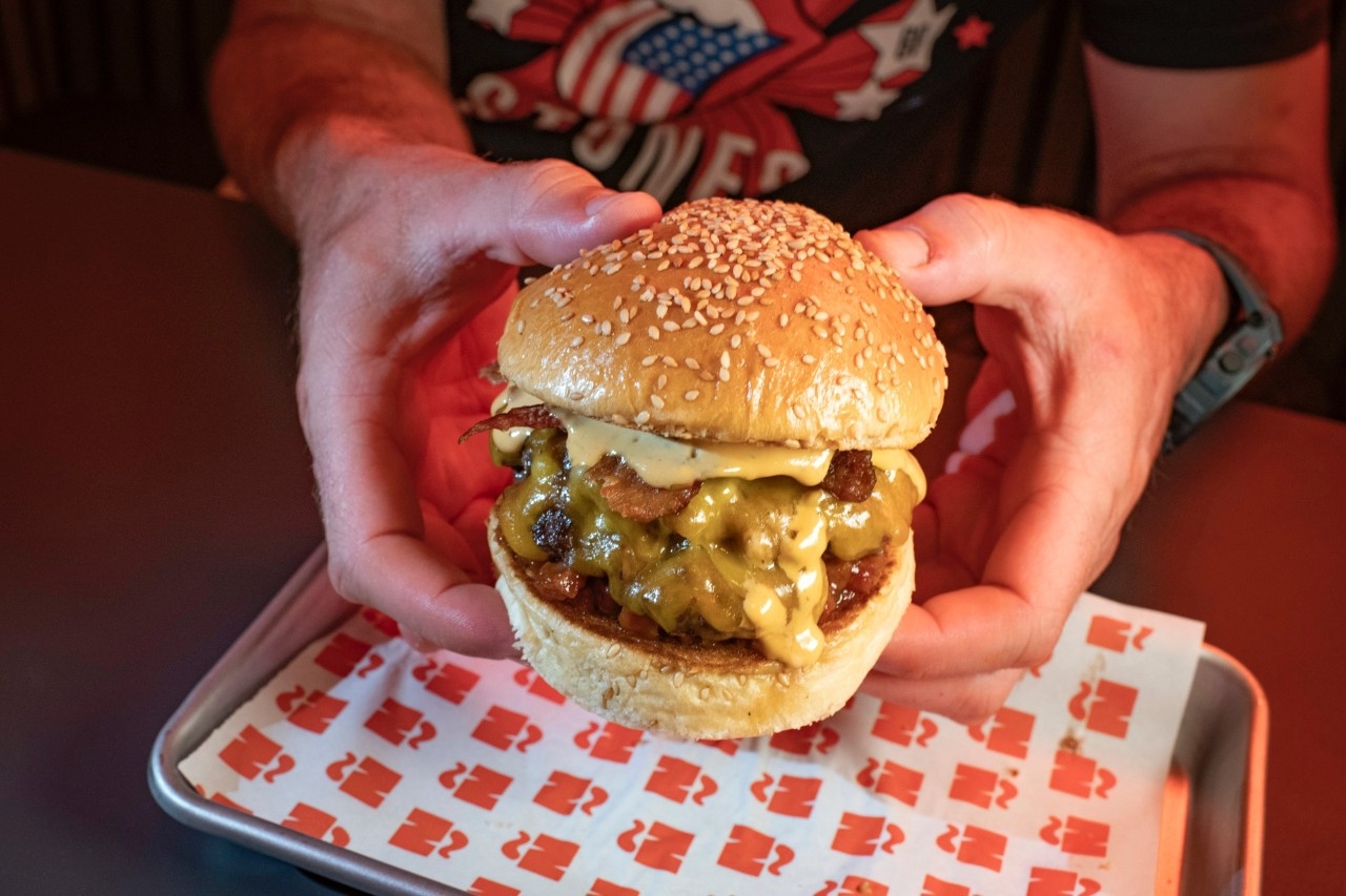 Hamburguesa Bacon Mama. Doble de carne de vaca gallega Lio madura 60 días, doble de queso Cheddar, Chutney de Bacon, doble de Bacon crujiente, doble de queso Cheddar, salsa de queso Cheddar y pimienta entre un pan blanco esponjoso de sésamo.