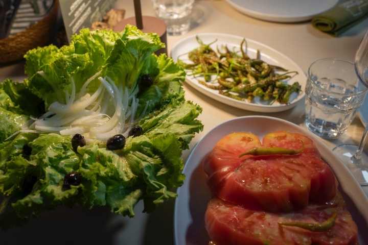 Tomate gordo, cortado como si fuera un chuletón con piparra y orégano fresco