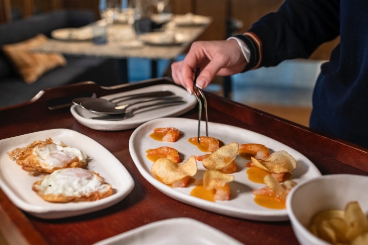 Las gambitas rojas al ajillo sobre patatas chips y huevos fritos con puntilla.