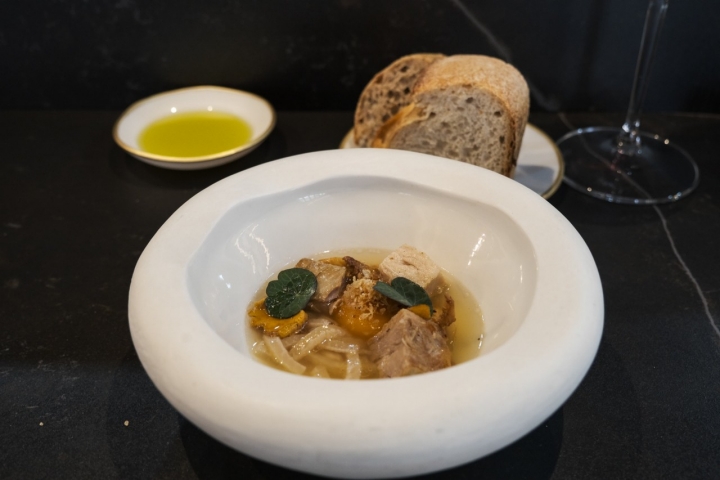 Sopa con yema confitada con daditos de panceta y fideos de piel de cerdo.