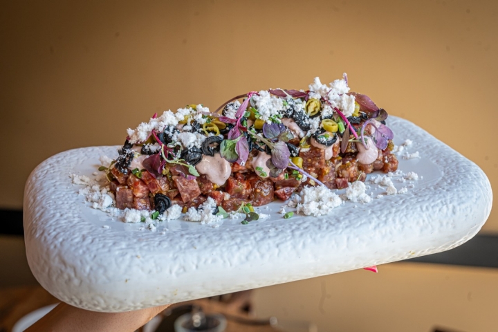 Cambirls 20-08-2022 Guía Repsol.                      Segundo restaurante de la ruta: Instint Restaurant. TÁRTAR DE FUET CAMPESINOCon tomate, “piparras”, kalamata y aceite de oliva. AUTOR: MANU MITRU.