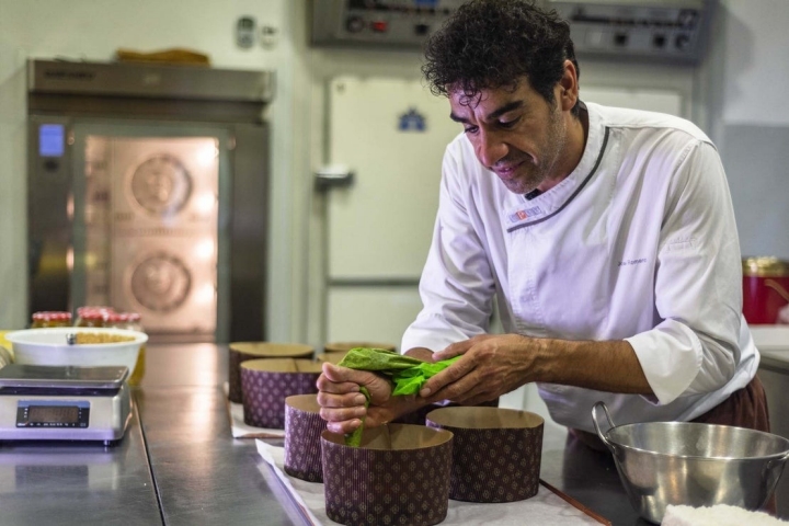 José echa con una manga pastelera la glasa que decora y da textura a la superficie del panettone.