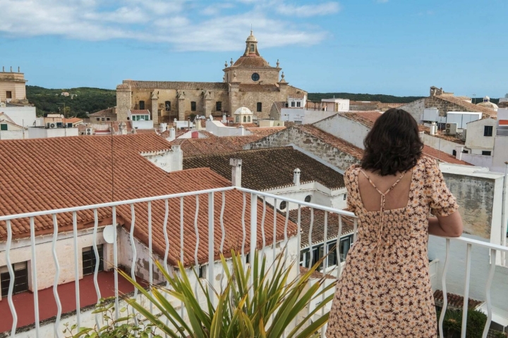 Una mujer mira desde la terraza de una habitación las vistas de Mahón.