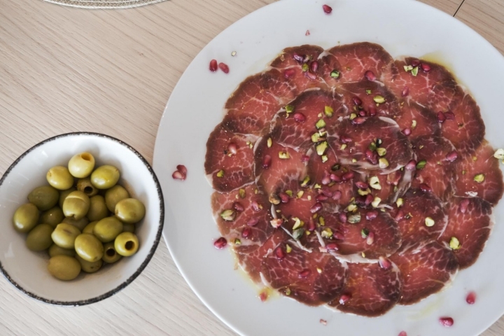 Carpaccio de presa ibérica con granada y pistachos.
