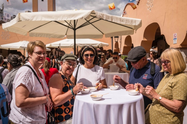 Un grupo de personas se comen la garbanzada en una mesa alta.