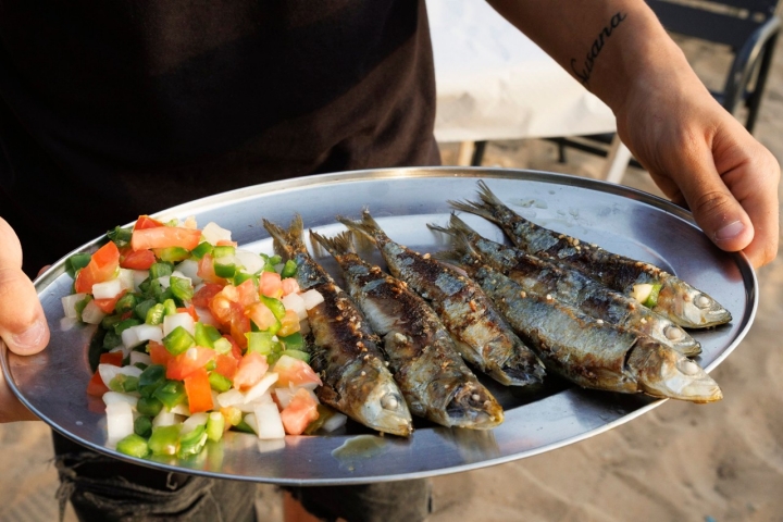 Sardinas a la brasa con los pies en la arena. Foto: Juan Carlos Toro