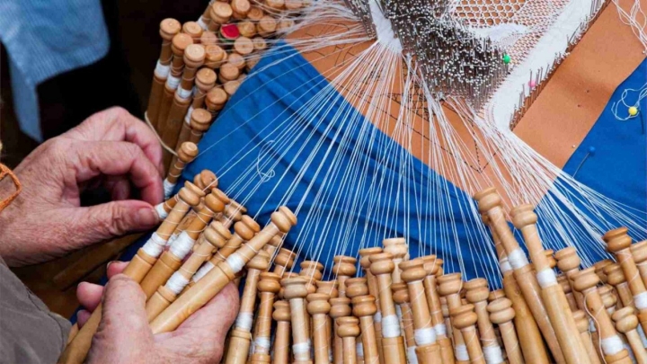 Manos trabajando el encaje de bollillos.