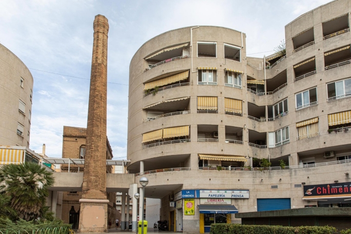 Esta chimenea aparece como por arte de magia sobre la acera, caprichosamente encastrada en un cuerpo de viviendas.