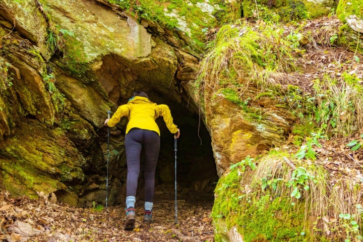 Una mujer se asoma a una pequeña cueva en la ruta por el barranco del Bornova (Guadalajara).