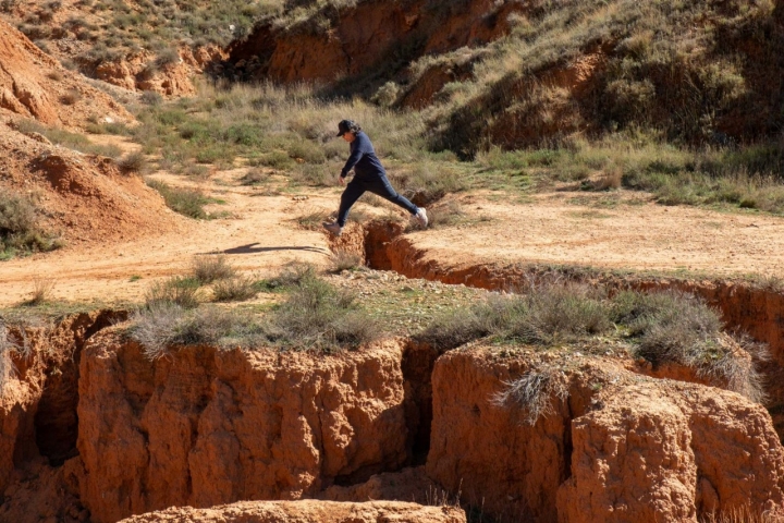 Un visitante salta una de las grietas del suelo