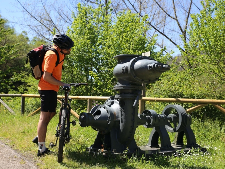 Ciclista contemplando una maquinaria ferroviaria en la ruta del Valle del Turón
